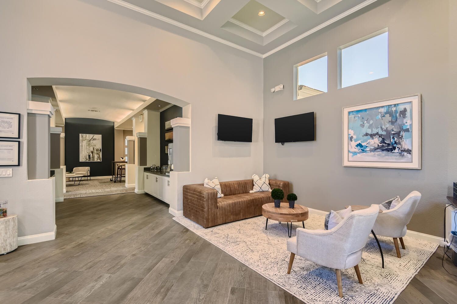 Modern apartment lobby with arched entry, two mounted TVs, and seating area at Alicante Apartments in Aliso Viejo, CA.
