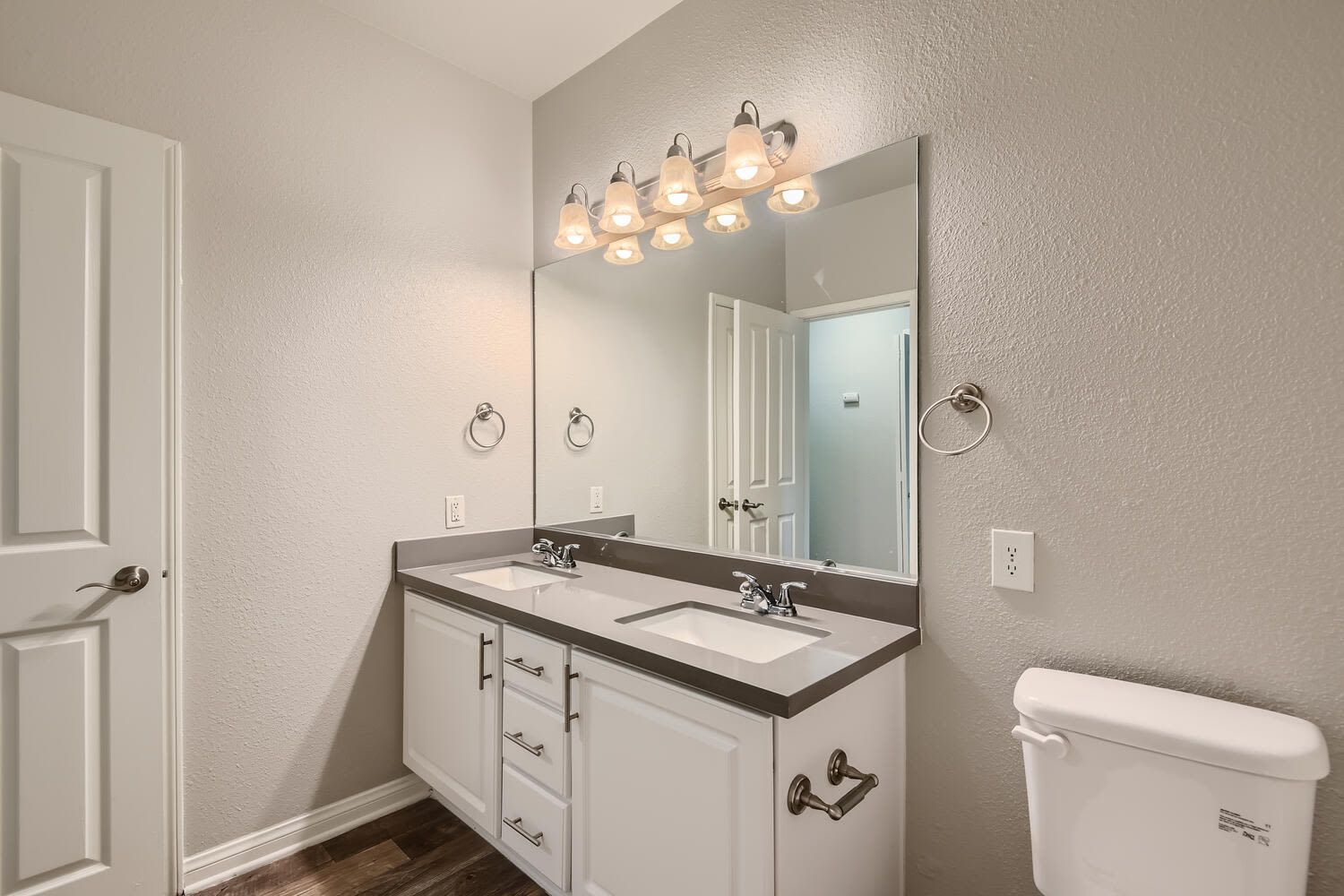 Bathroom vanity with dual sinks, large mirror, and modern light fixture at Alicante Apartments in Aliso Viejo, CA.