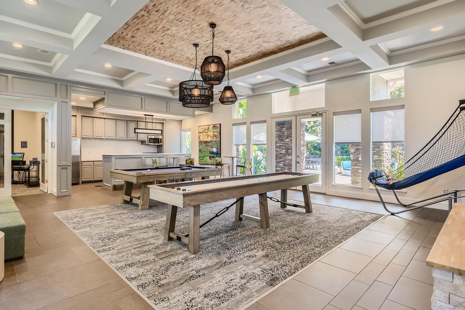 Interior of a community clubhouse with billiards tables, a kitchenette, and lounge seating at Alicante Apartments in Aliso Viejo, CA.