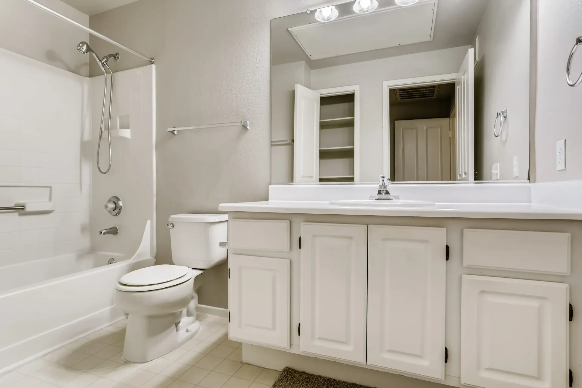 White bathroom with a tub/shower combo, toilet, and a wide vanity at Alicante Apartments in Aliso Viejo, CA.