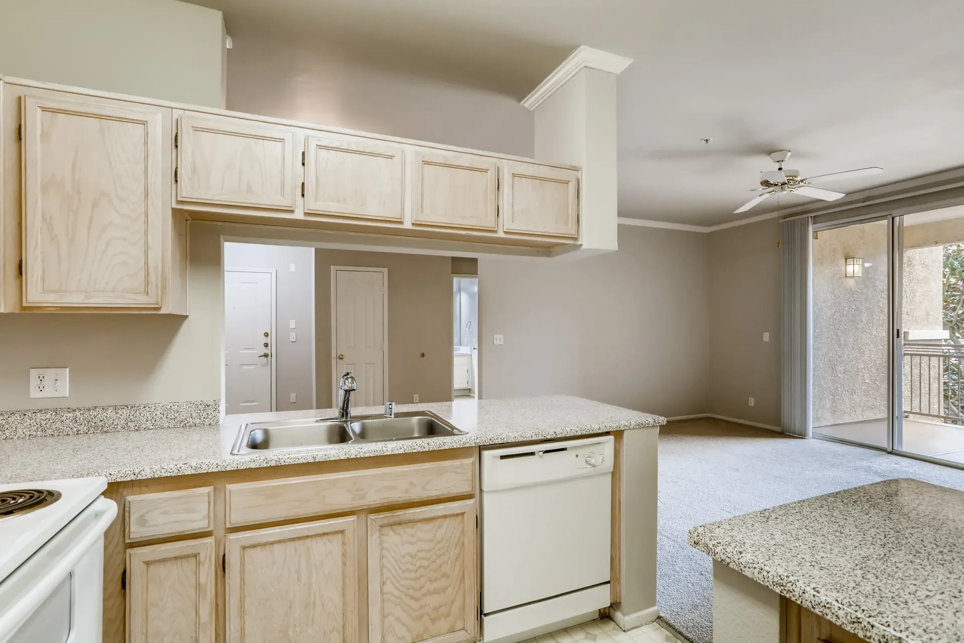 Open-concept kitchen with light wood cabinets, speckled counters, and view into the living area at Alicante Apartments in Aliso Viejo, CA.