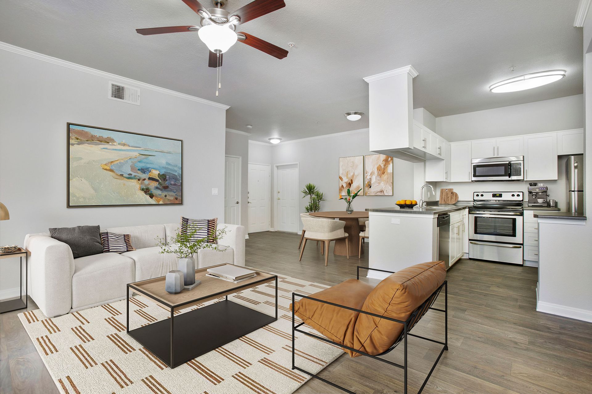 Open-concept living room and kitchen in a modern apartment with white cabinets and stainless appliances at Alicante Apartments in Aliso Viejo, CA.