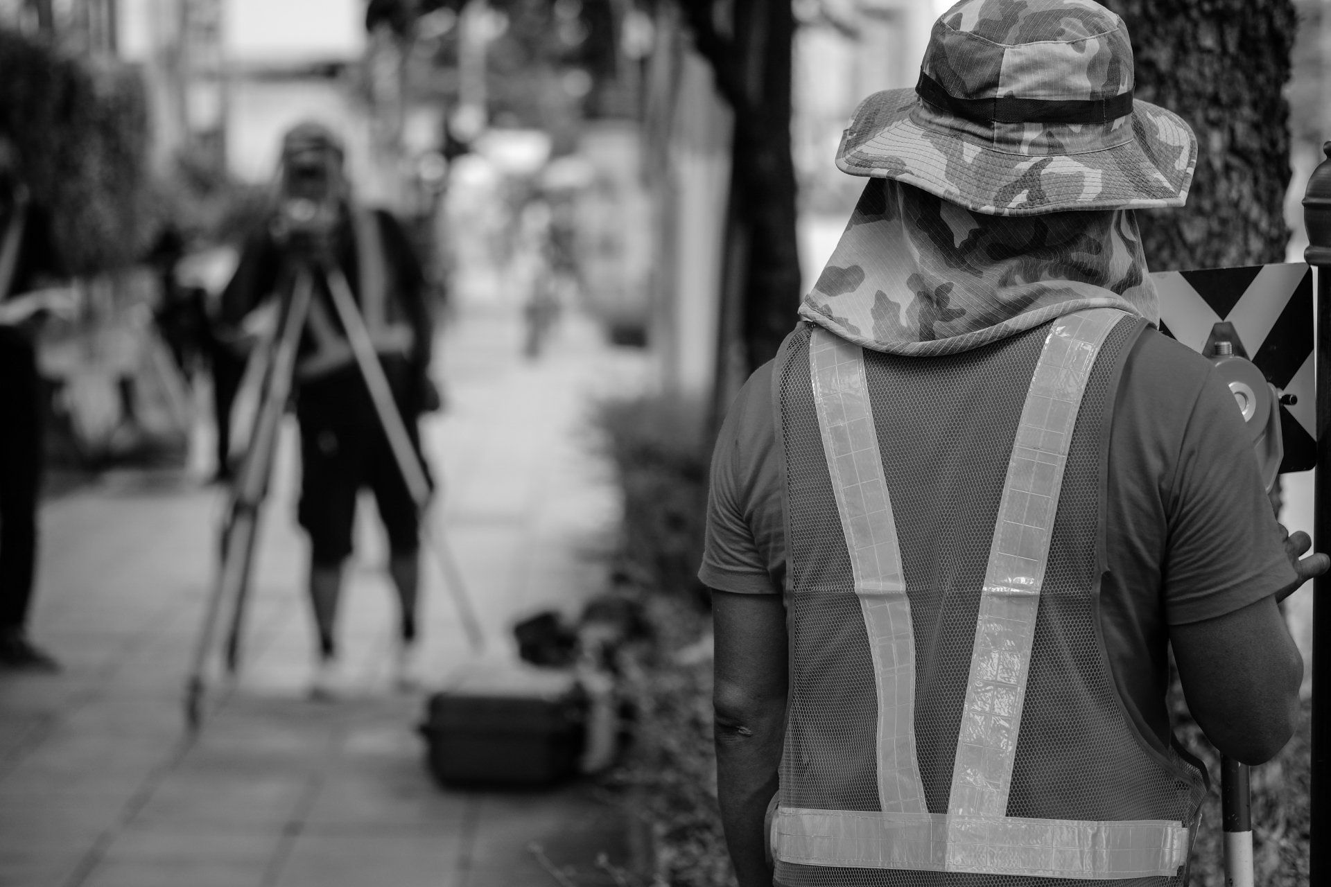 Une photo en noir et blanc d'un homme portant un gilet de sécurité et un chapeau.