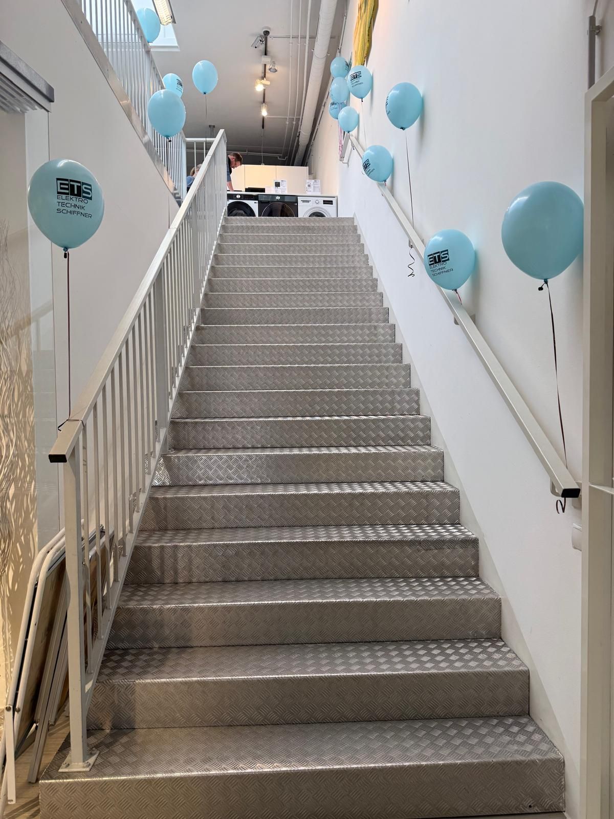 Metalltreppe mit blauen Luftballons an Wänden und Geländer.