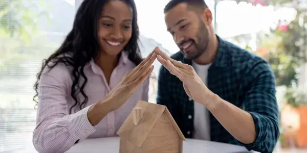 Two people smiling and forming a heart shape over a paper shopping bag