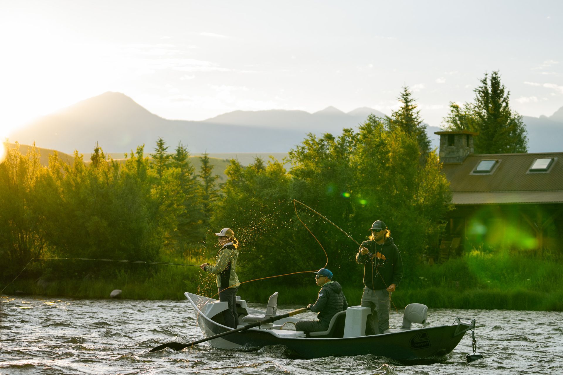 Drift boat with two fly fishing anglers floating down the Madison River at sunrise