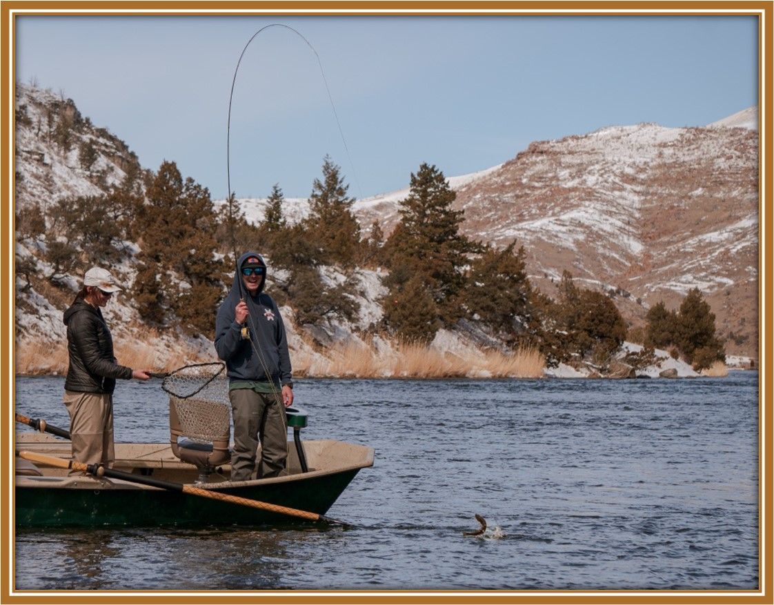 2 People Fly Fishing With a Fish on the line.