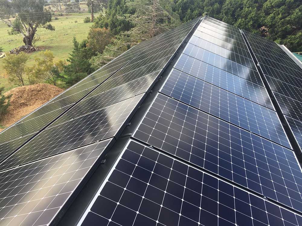 Row Of Solar Panels On A Roof With Trees In The Background — Goulburn Solar In Goulburn, NSW