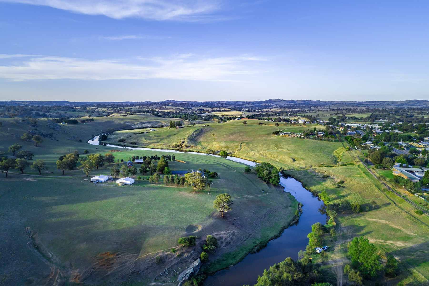 Aerial View Of A River Flowing Through A Lush Green Field — Goulburn Solar In Yass, NSW