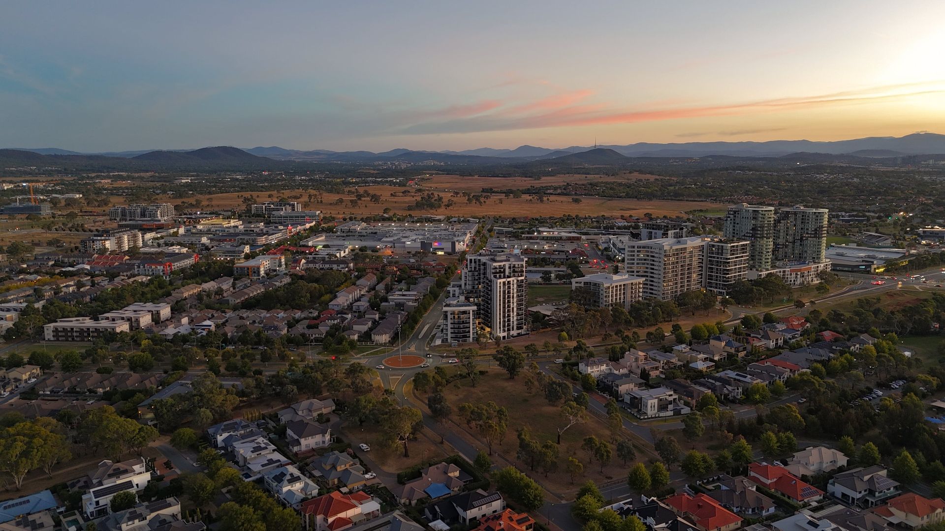City at Sunset With Apartment Blocks, Roads, and Distant Hills — Goulburn Solar In Gungahlin, ACT