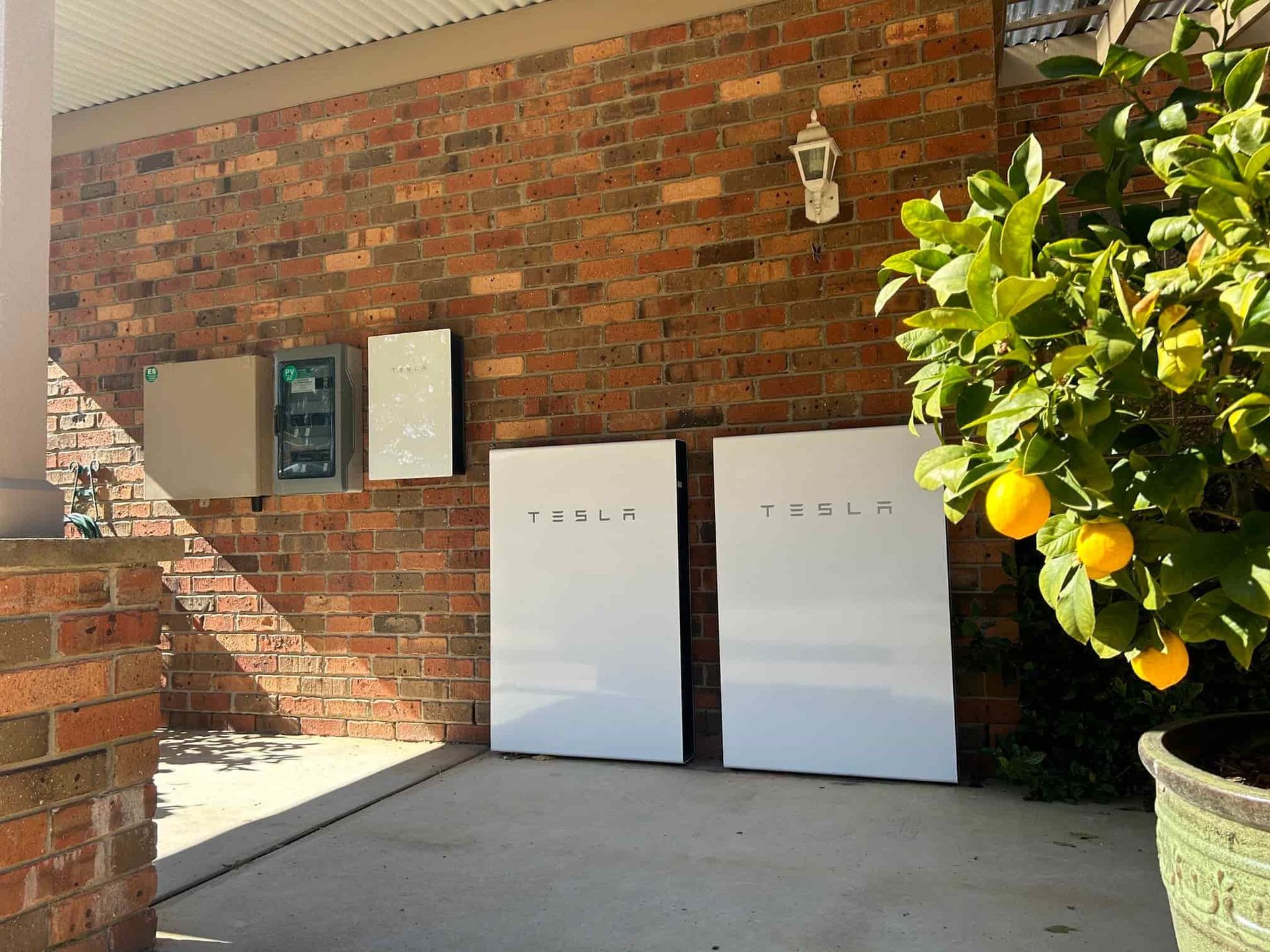 Brick Wall With Two Tesla Batteries On It — Goulburn Solar In Picton, NSW