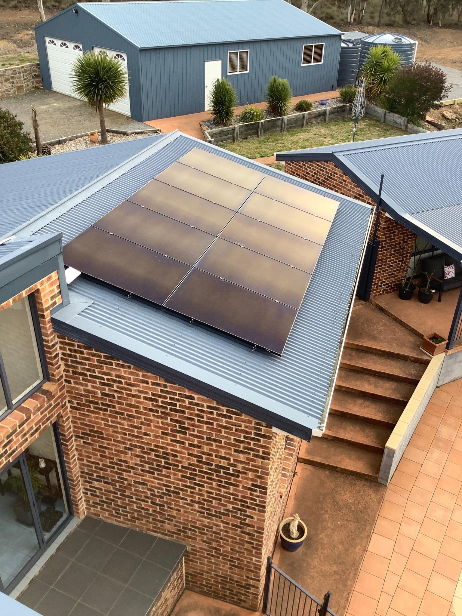Aerial View of Brick Homes with Blue Metal Roofs and Rooftop Solar Panels — Goulburn Solar In Goulburn, NSW