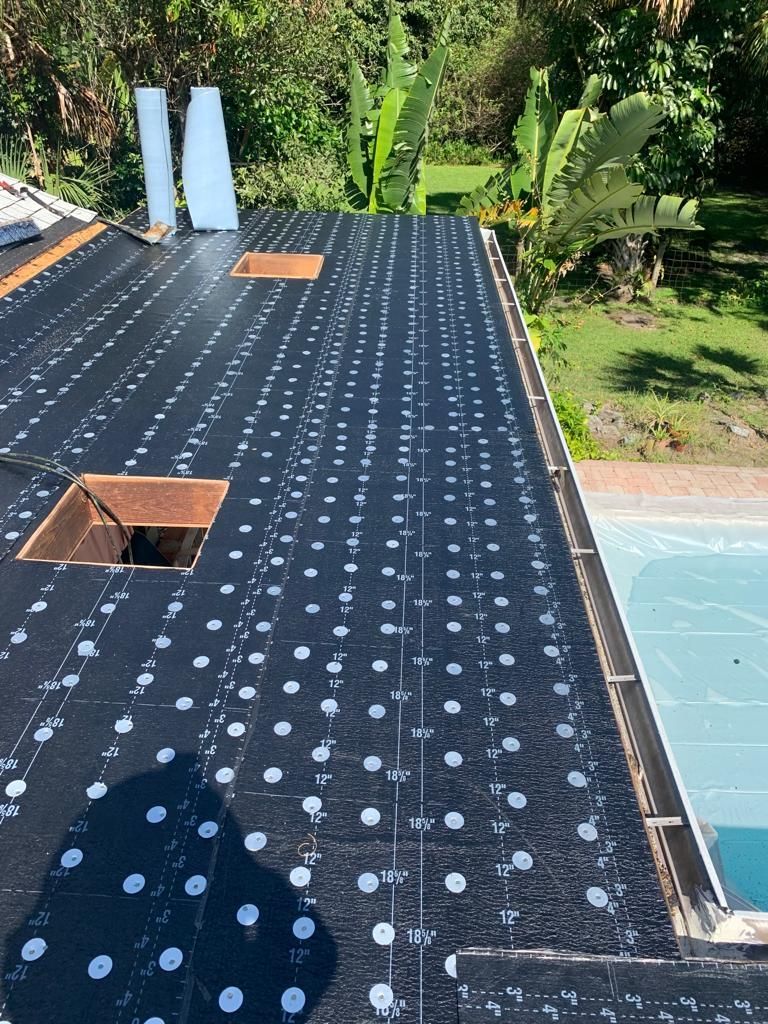 Roof under construction: black underlayment with white dots, open skylight, near a pool.