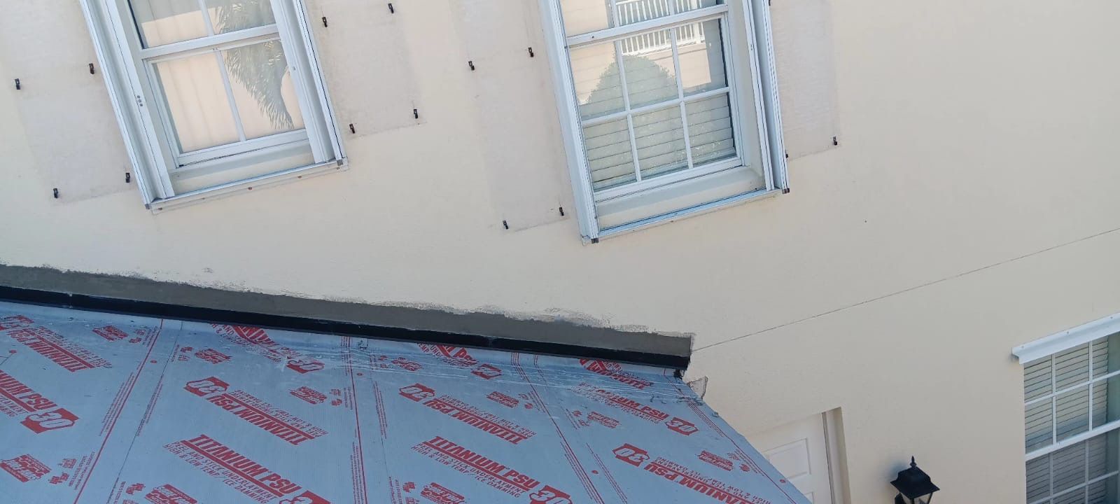 Exterior of a building with windows, a new roof, and a light fixture.