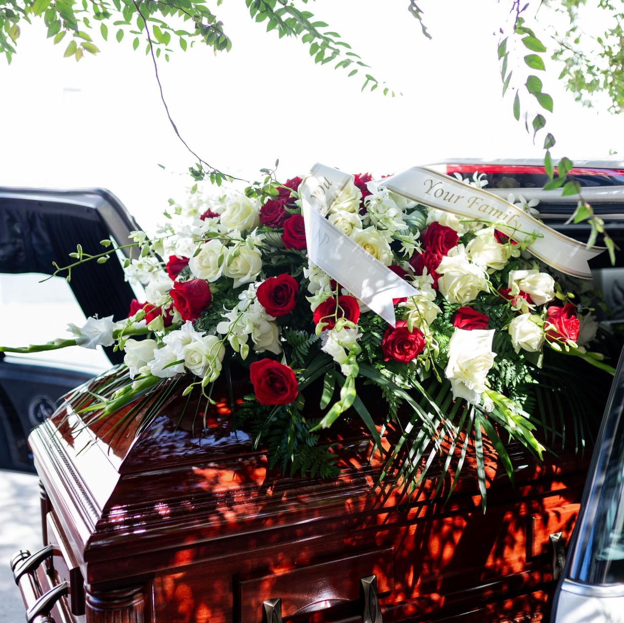 a coffin with flowers and a ribbon that says 
