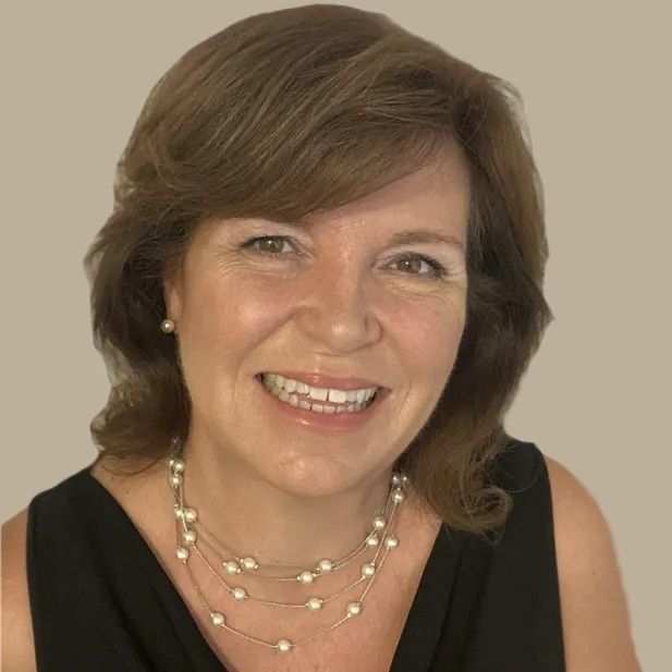 Woman with dark hair smiles, wearing a pearl necklace and sleeveless black top.