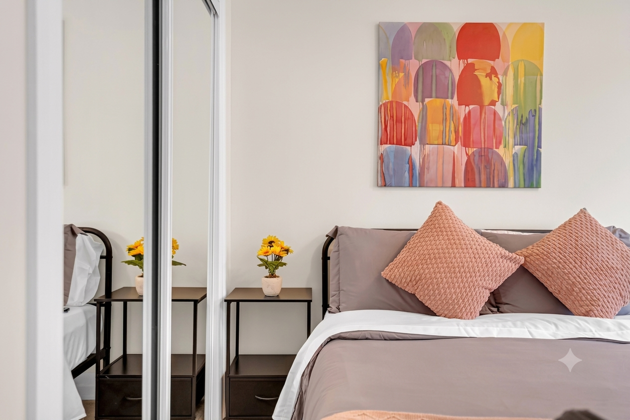 Modern bedroom with bed, mirrored closet, side tables, and colorful wall art