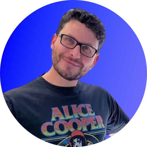 Smiling man in glasses and a black Alice Cooper T-shirt against a blue background