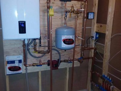 A room with a lot of pipes and a boiler on the wall.