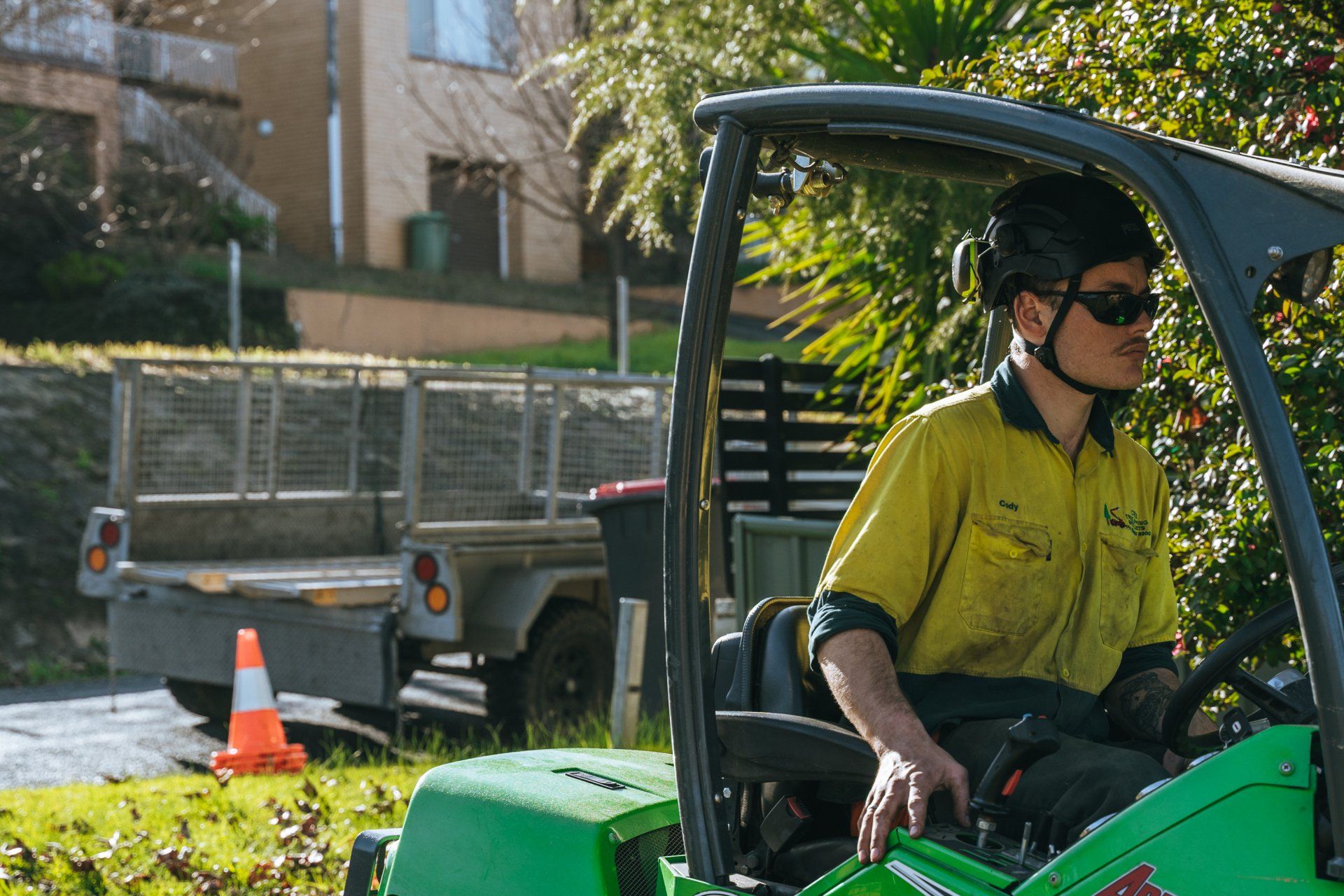 A man in a yellow shirt is driving a green tractor
