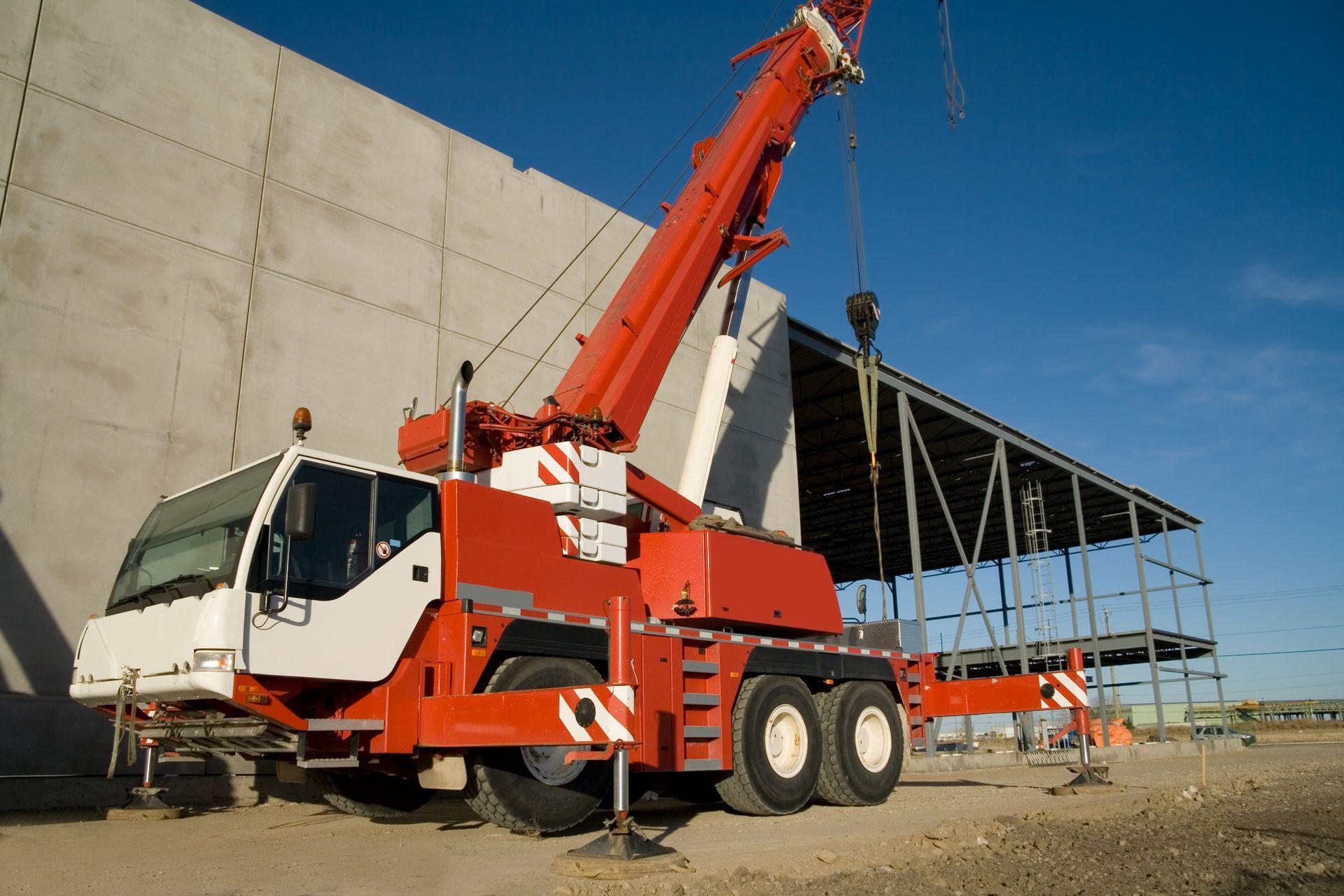 A red and white crane is parked in front of a building under construction