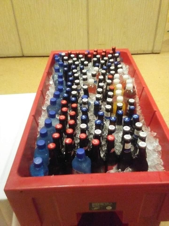 Red crate filled with assorted bottles arranged in rows on a floor indoors