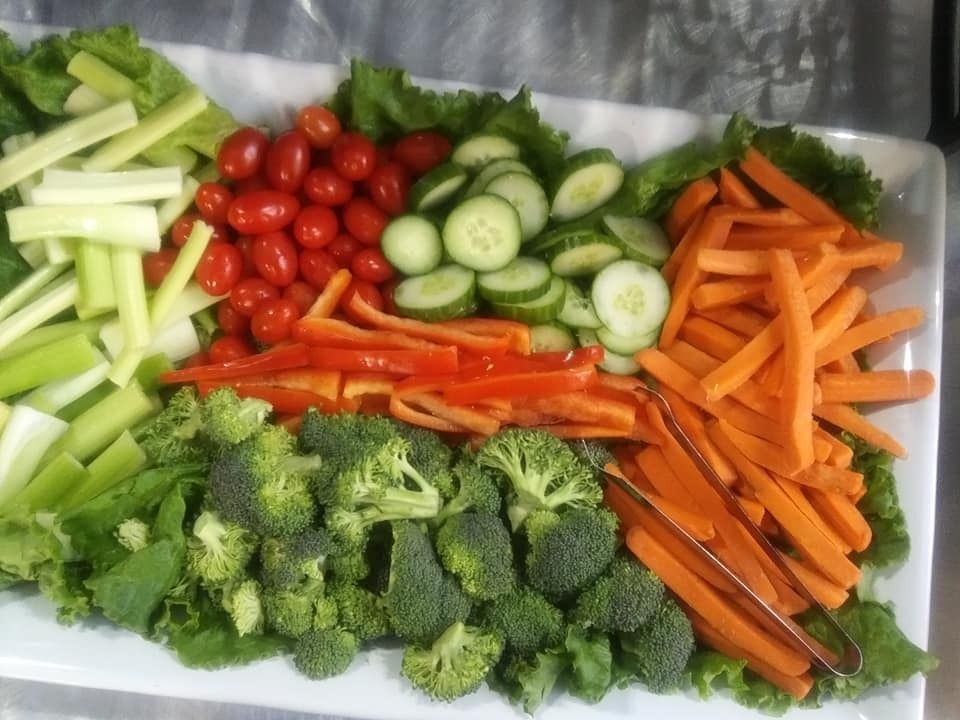 Assorted fresh vegetables—broccoli, carrots, cucumbers, cherry tomatoes, and celery—neatly arranged on a tray