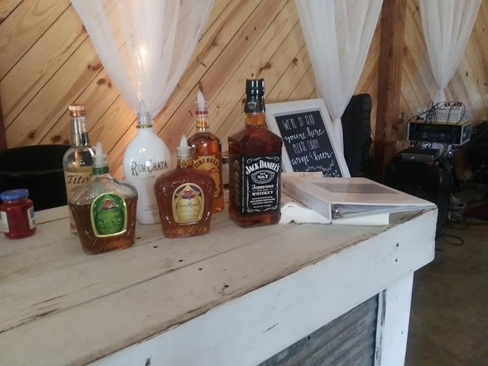 Assorted liquor bottles on a wooden shelf in a cozy bar or tasting room
