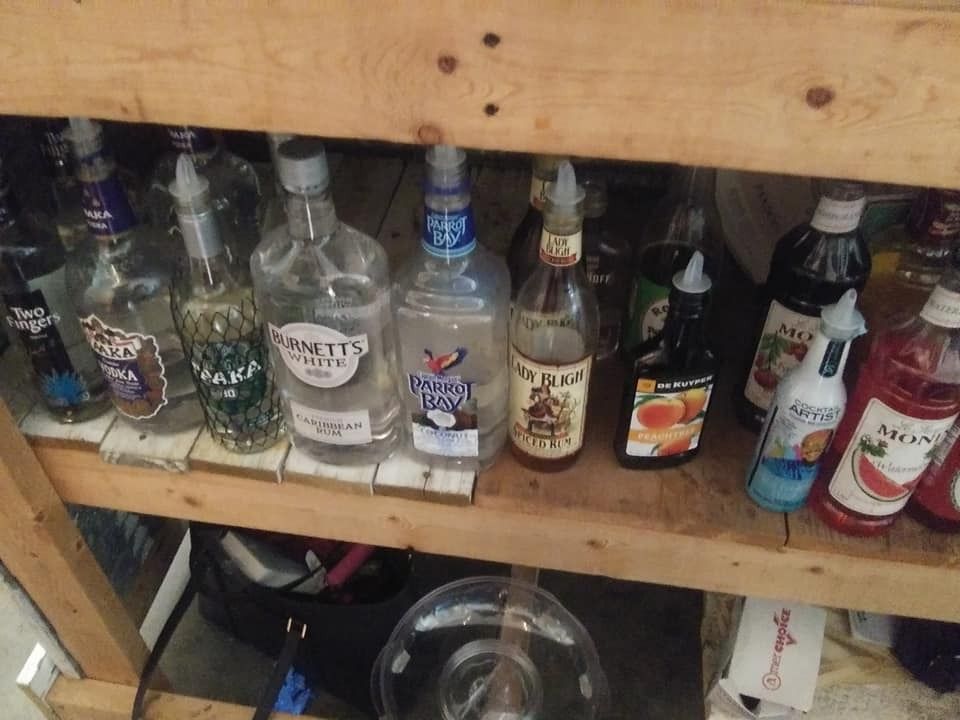 Shelves of assorted liquor bottles stored under a wooden counter