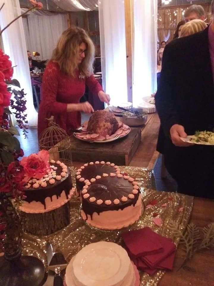 Dessert buffet with cakes and pastries on a table; two people serving food in the background