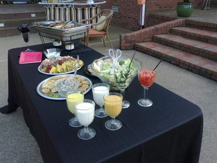Outdoor buffet table with salads, fruit, and drinks on a patio ליד steps