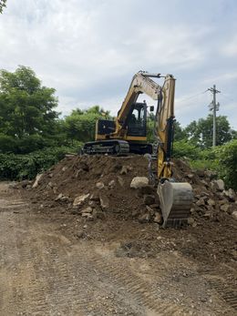 Construction site: excavator, bulldozer, truck with a load, and cleared land.