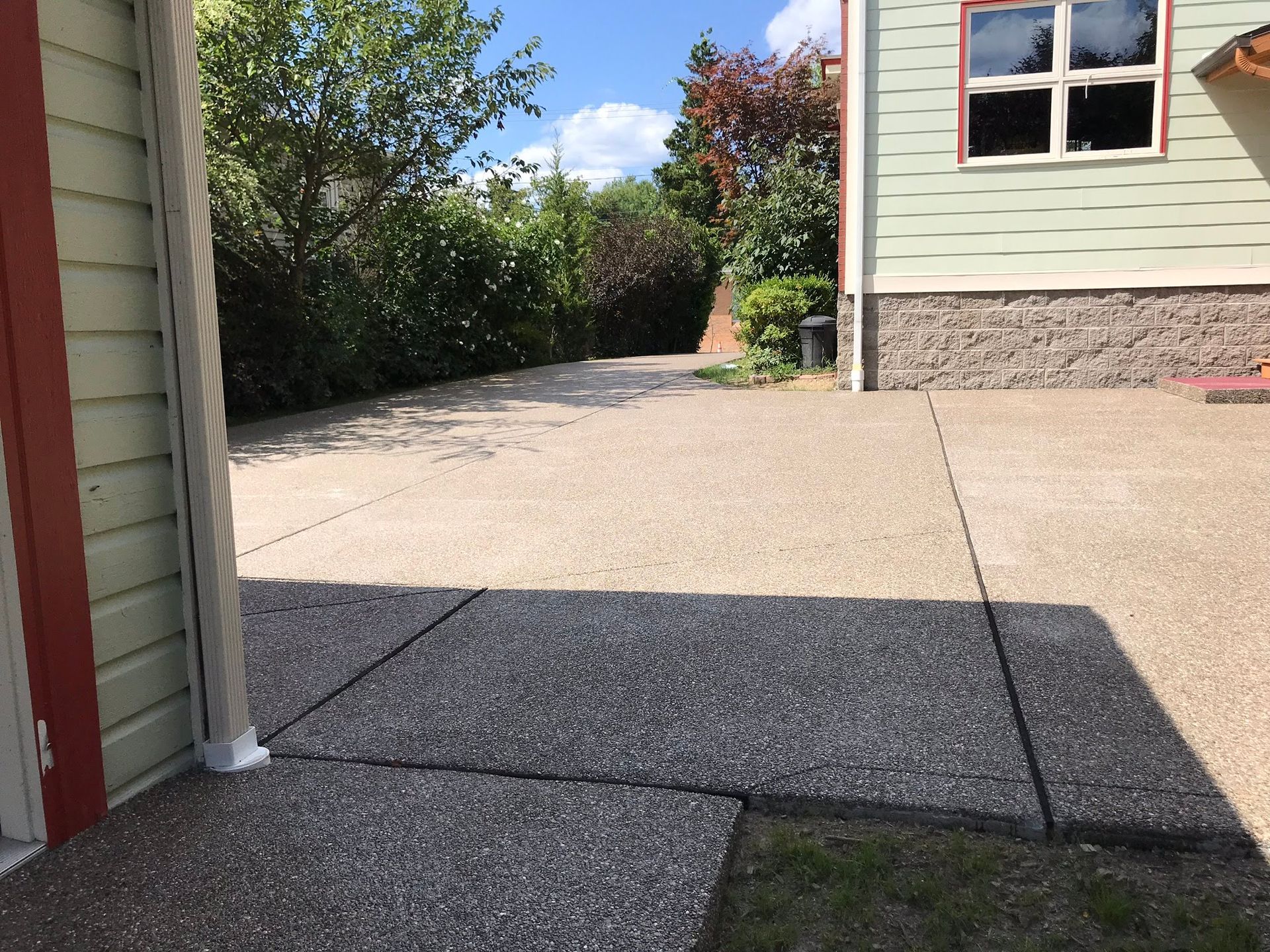 Concrete patio with stone building facade and greenery.