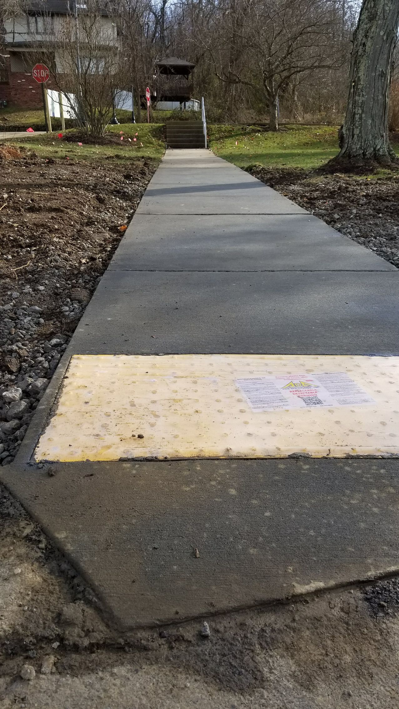 Concrete walkway leading to a structure, with a yellow and white section near the bottom.
