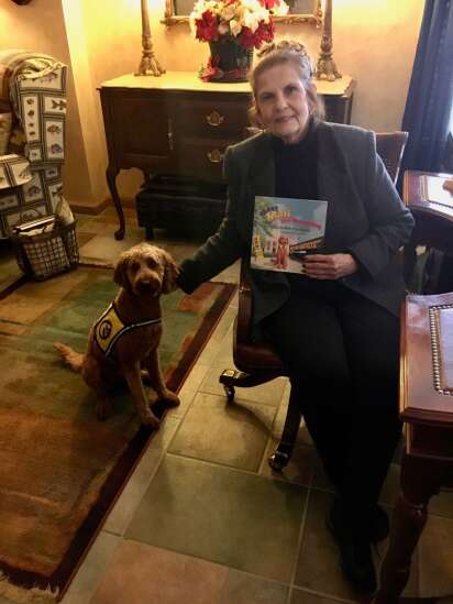 Woman posing next to her therapy dog with a book in their living room