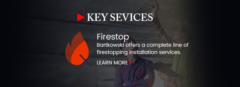 A man is standing in front of a sign that says key services firestop