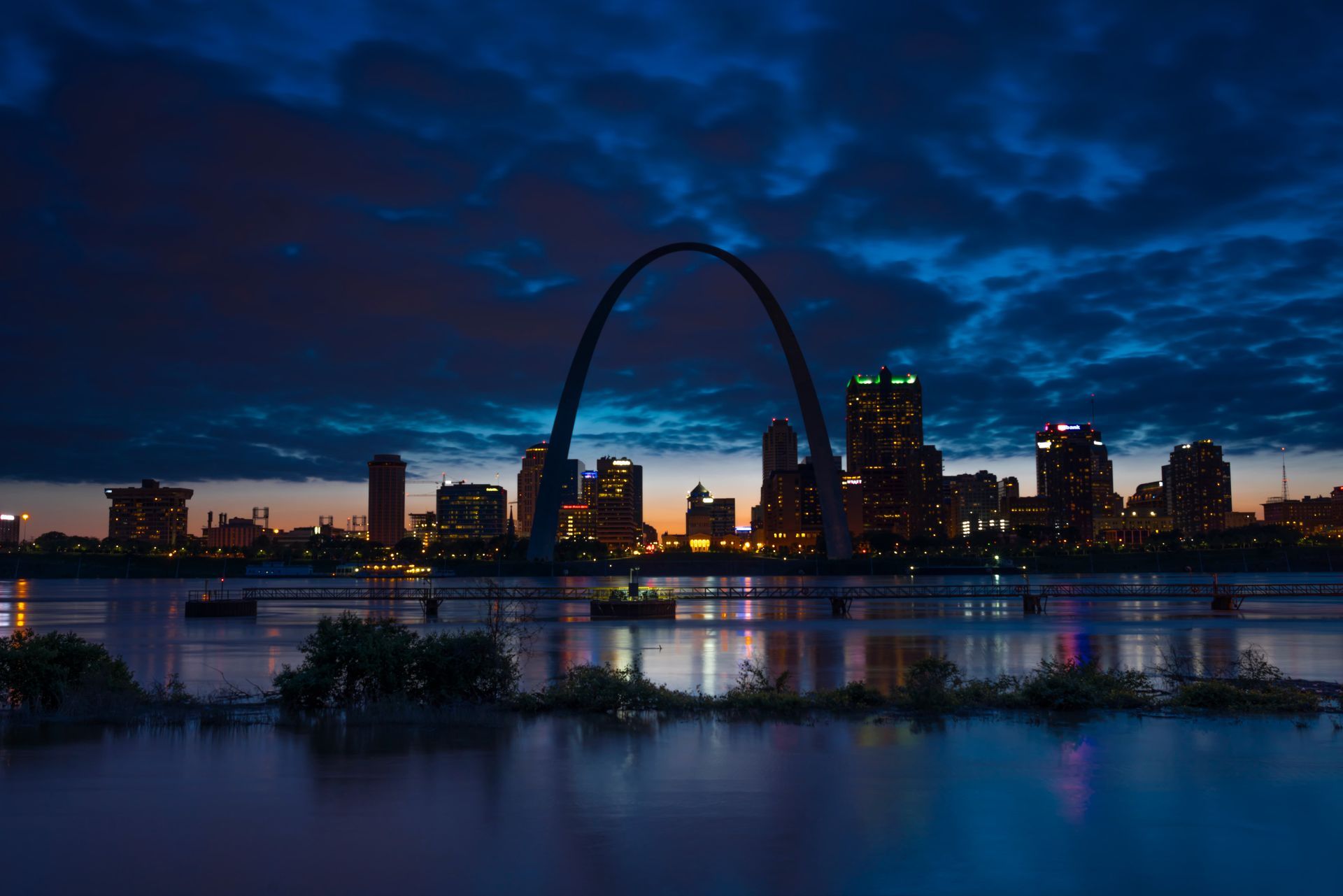 St. Louis Gateway Arch and skyline at dusk, reflected in the river under a blue evening sky