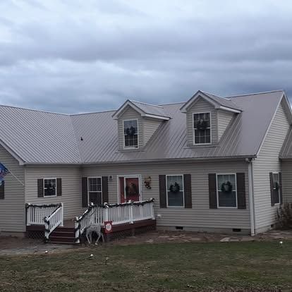 Single-story beige house with gray roof, front porch, and cloudy sky