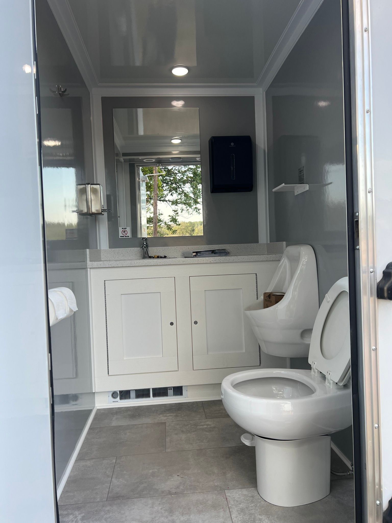 Small bathroom with white vanity, toilet, shower, and gray walls.