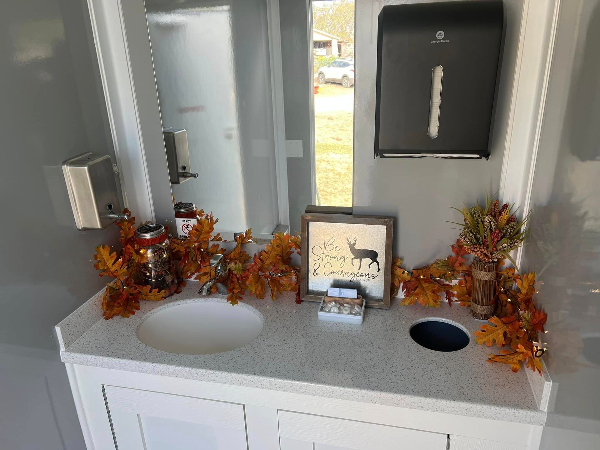 White bathroom vanity with two sinks, mirrors, and autumn leaf decor on the countertop