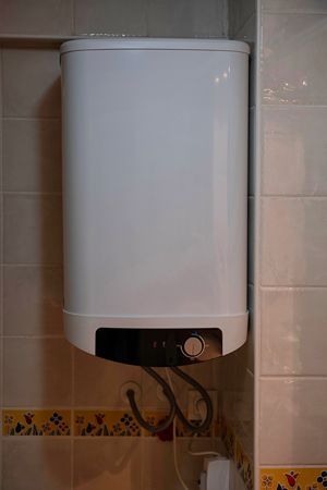 A Man Wearing A Hard Hat Is Fixing A Water Heater - Fulton, CA - Devoto Plumbing, Inc.