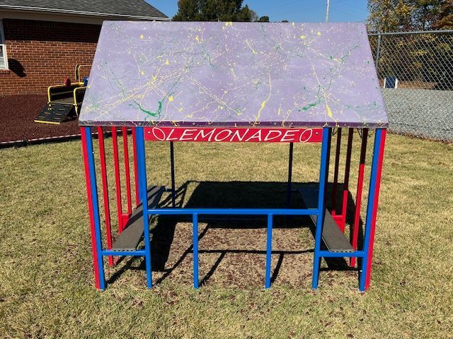 A picnic table with a roof that says lemonade on it