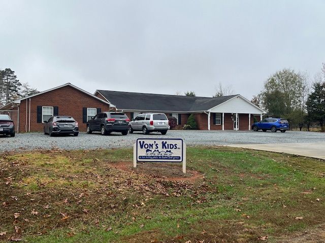 A row of cars are parked in front of a brick house.