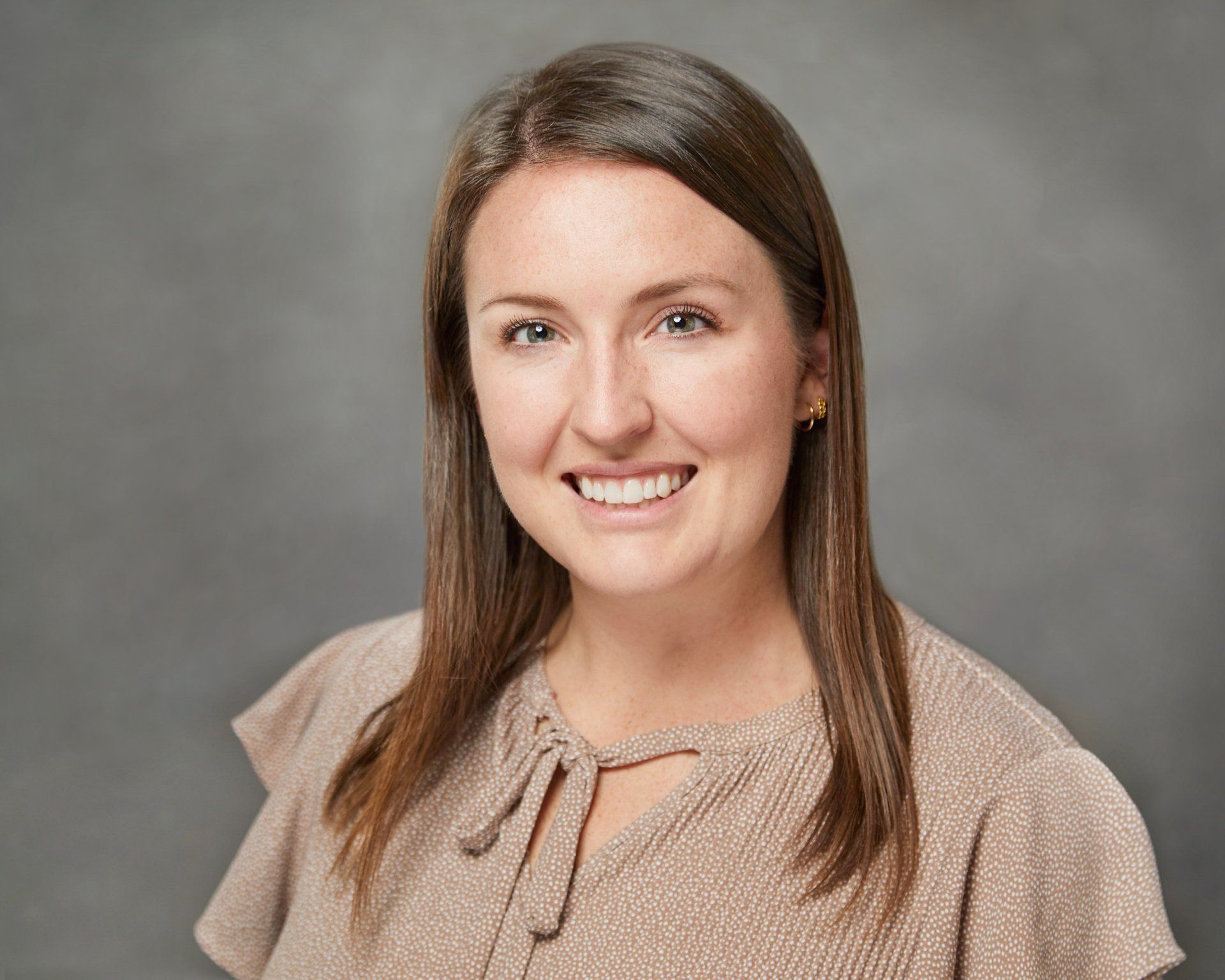 A woman in a brown shirt is smiling for the camera.