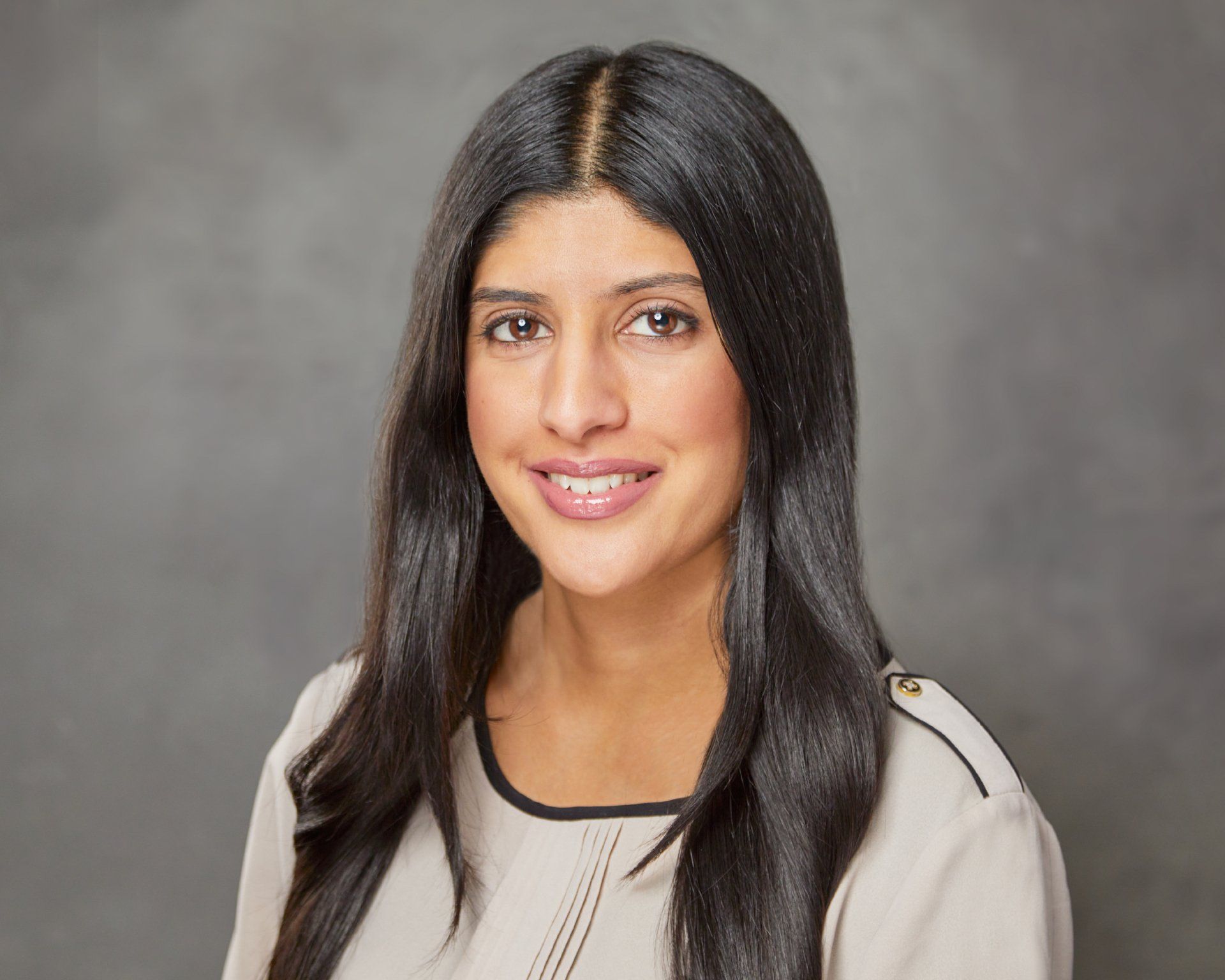 A woman with long black hair is smiling for the camera.