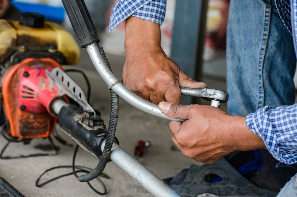 Person Using A Wrench To Repair A Weed Wacker Outdoors — Stihl Shop Atherton In Malanda, QLD