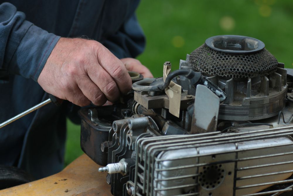 Person's Hands Working On A Lawnmower Engine — Stihl Shop Atherton In Yungaburra, QLD