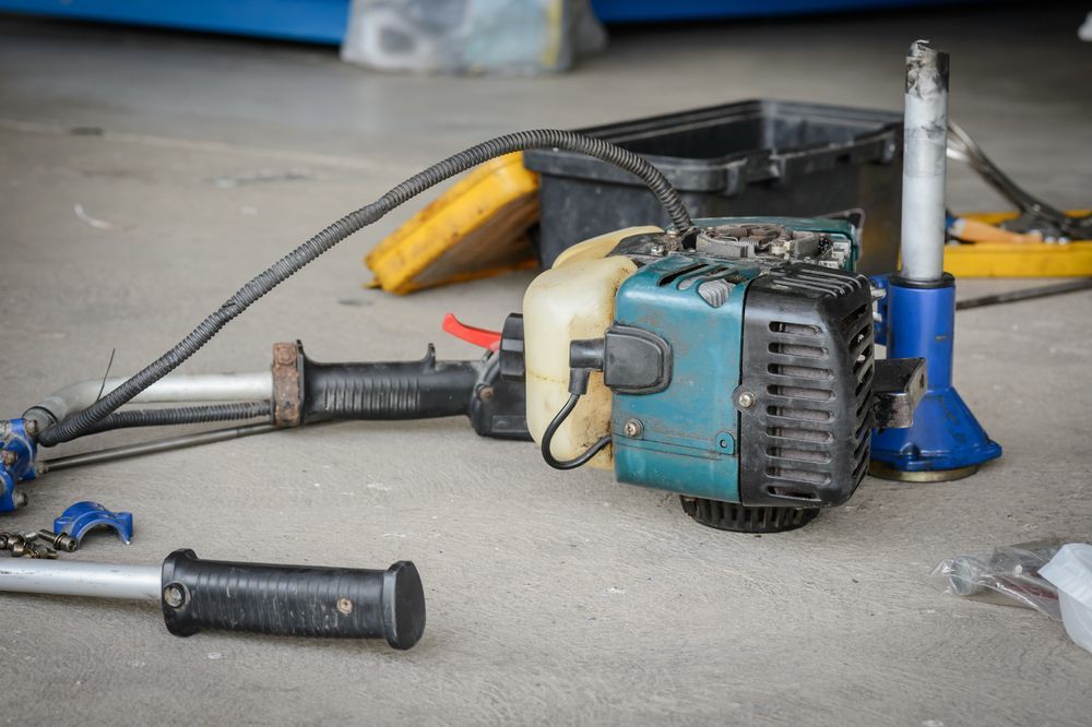 A Disassembled, Teal And Black Weed Whacker On A Concrete Surface — Stihl Shop Atherton In Malanda, QLD