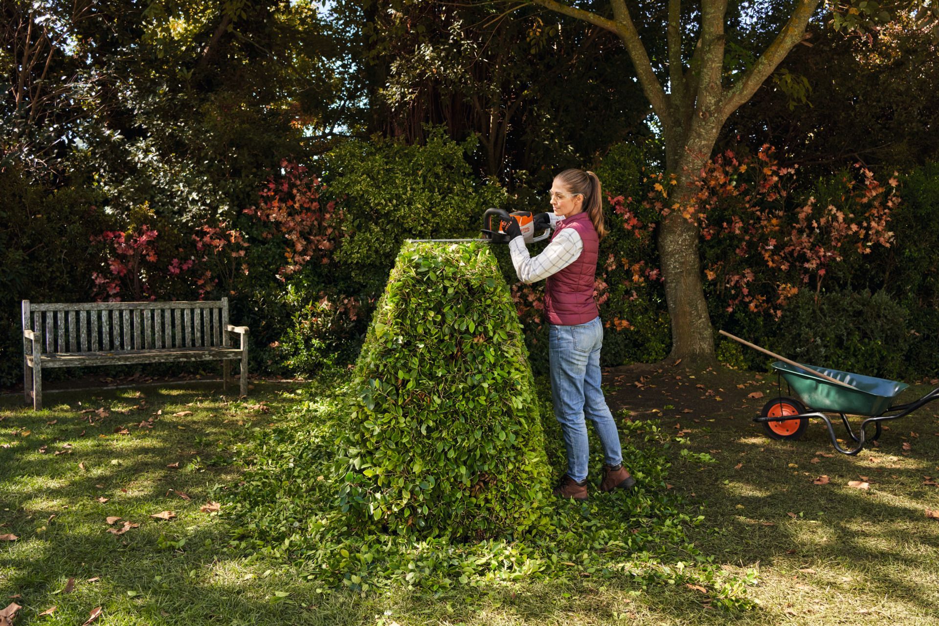 Woman Trimming A Large Bush In A Garden With Electric Shears — Stihl Shop Atherton In Yungaburra, QLD