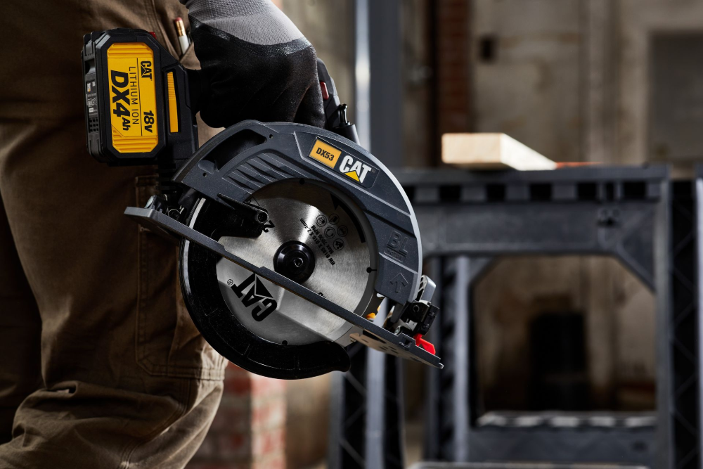 A person wearing work clothes holds a yellow and black CAT circular saw in an indoor workshop setting— Stihl Shop Atherton In Atherton, QLD